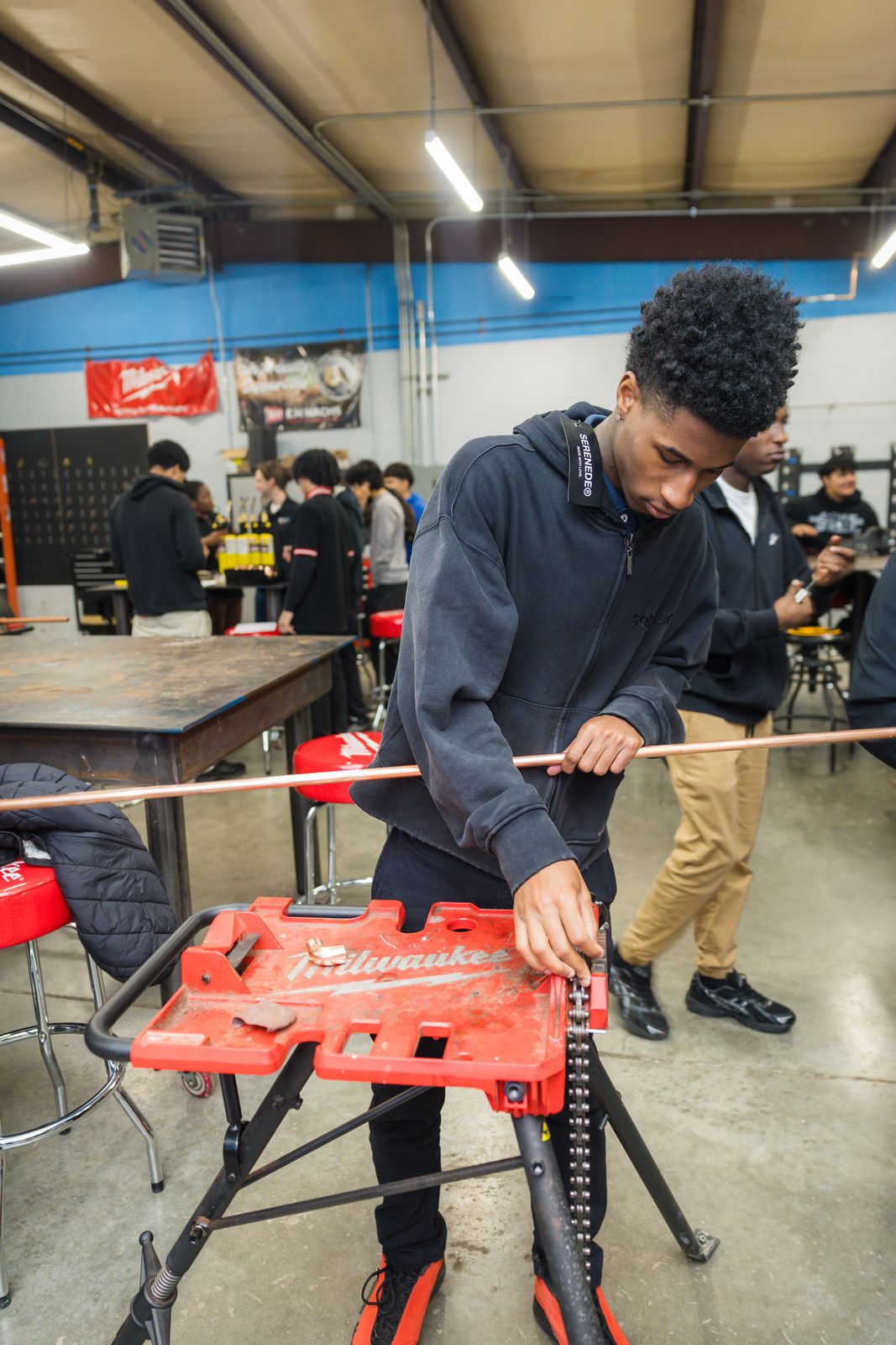 High school student cutting copper pipe during a career exploration day
