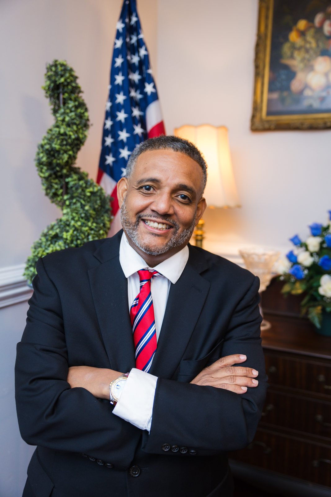 Brandon Brown with arms crossed beside an American flag