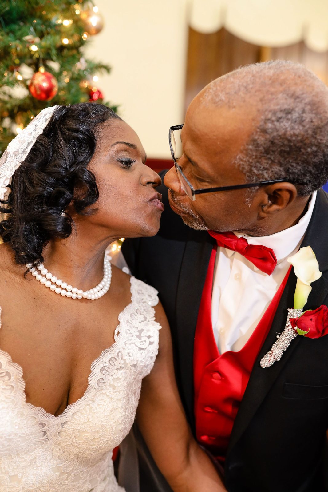 Bride and groom kiss by the Christmas tree