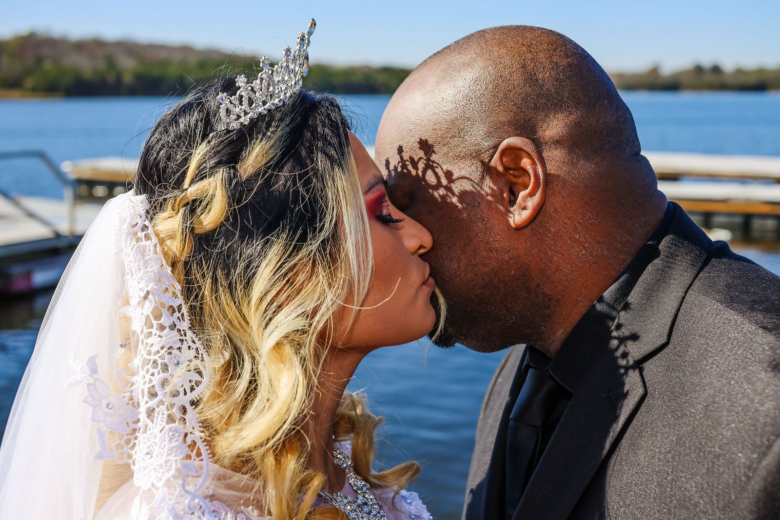 Bride and groom kiss by the lake